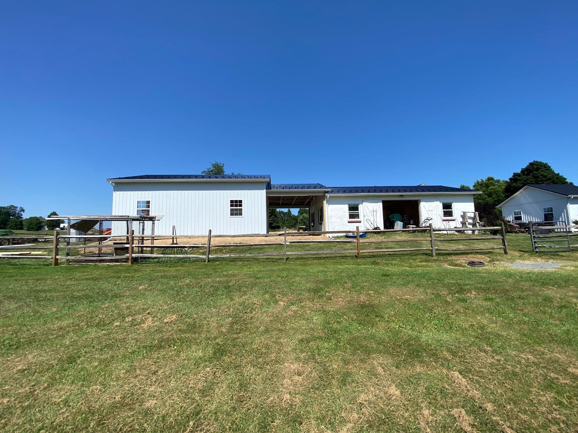 A white post frame building with black metal roof.