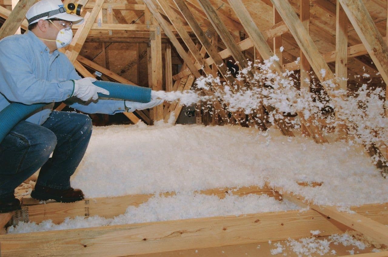A worker installs blown insulation.