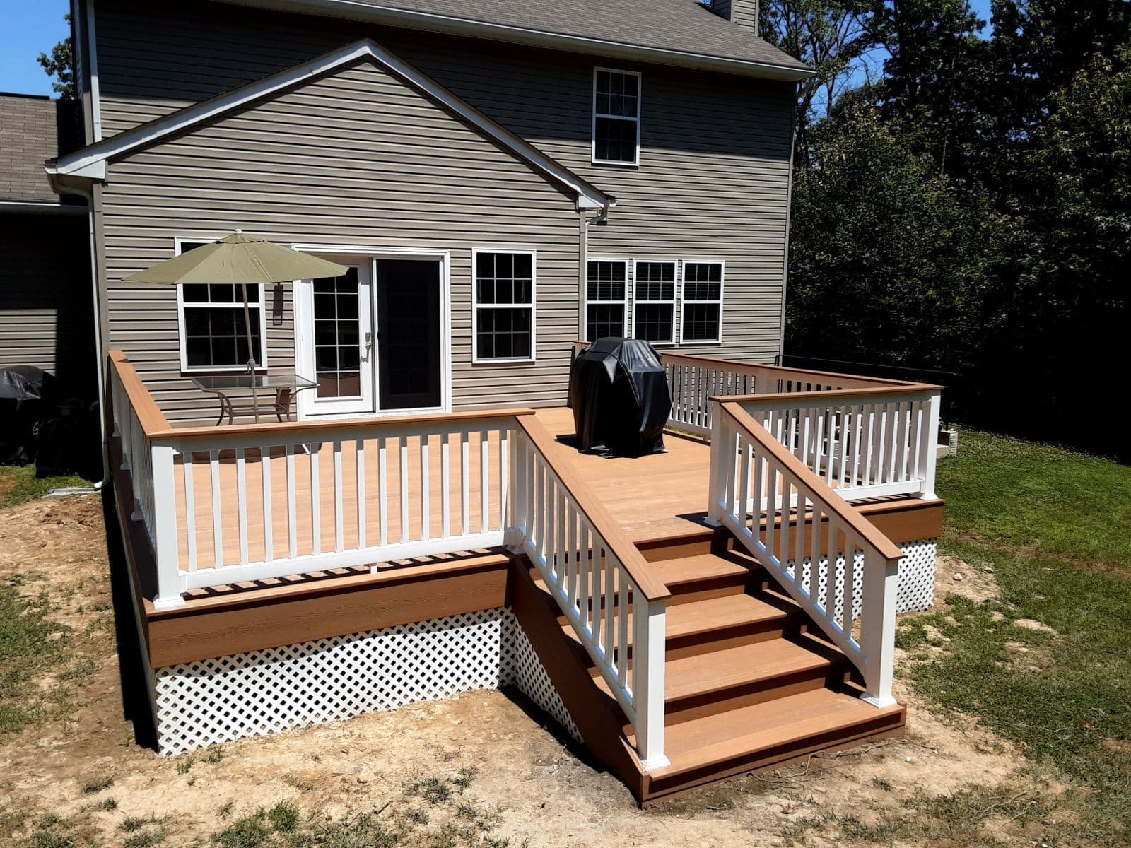 A white and brown deck off the back of a tan house.