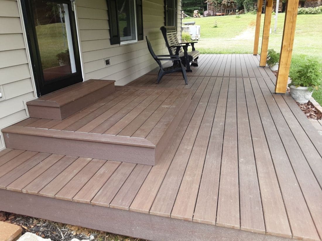 A newly-installed medium brown porch attached to a white house.