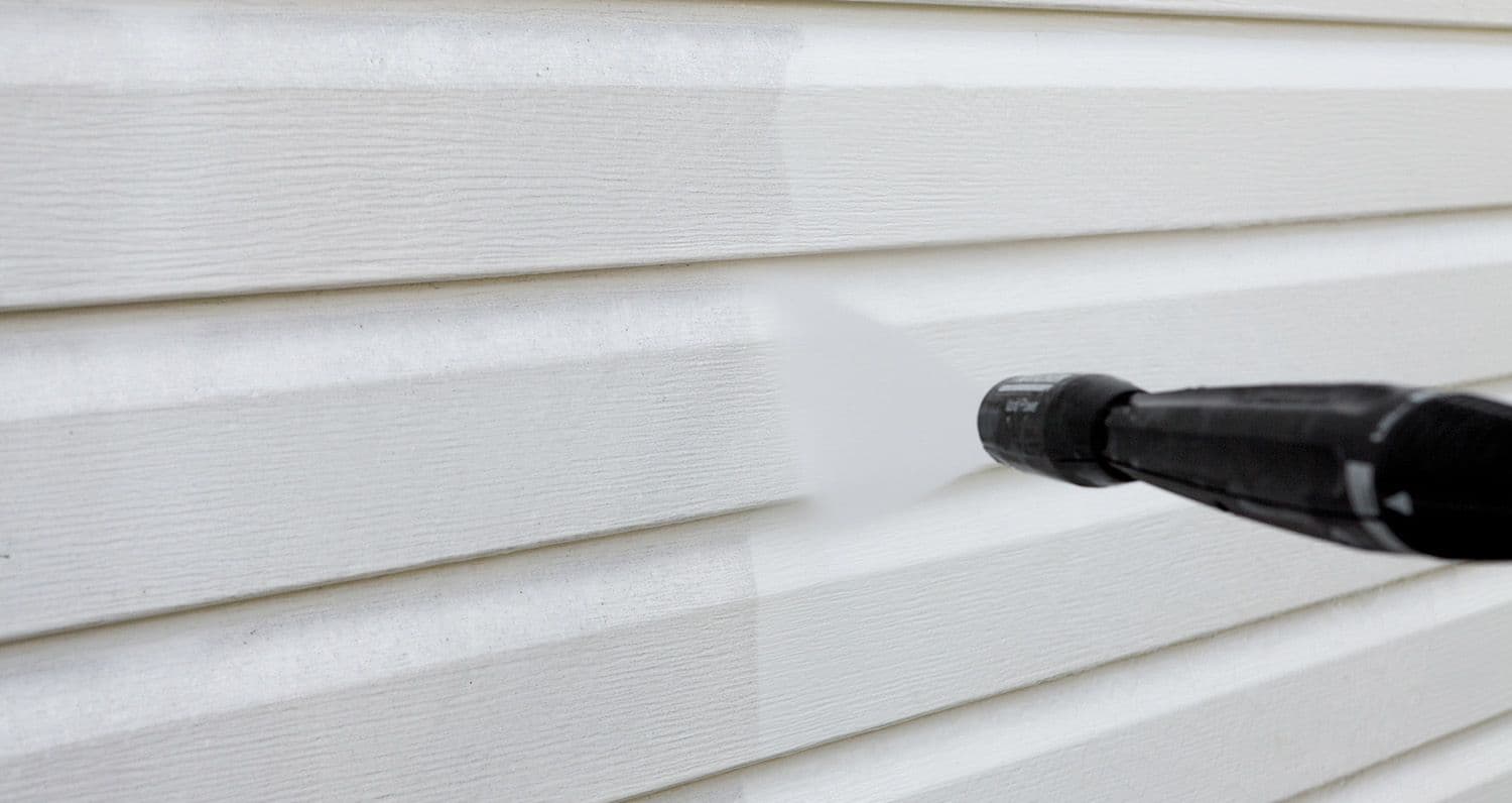 A close-up of siding being power washed.