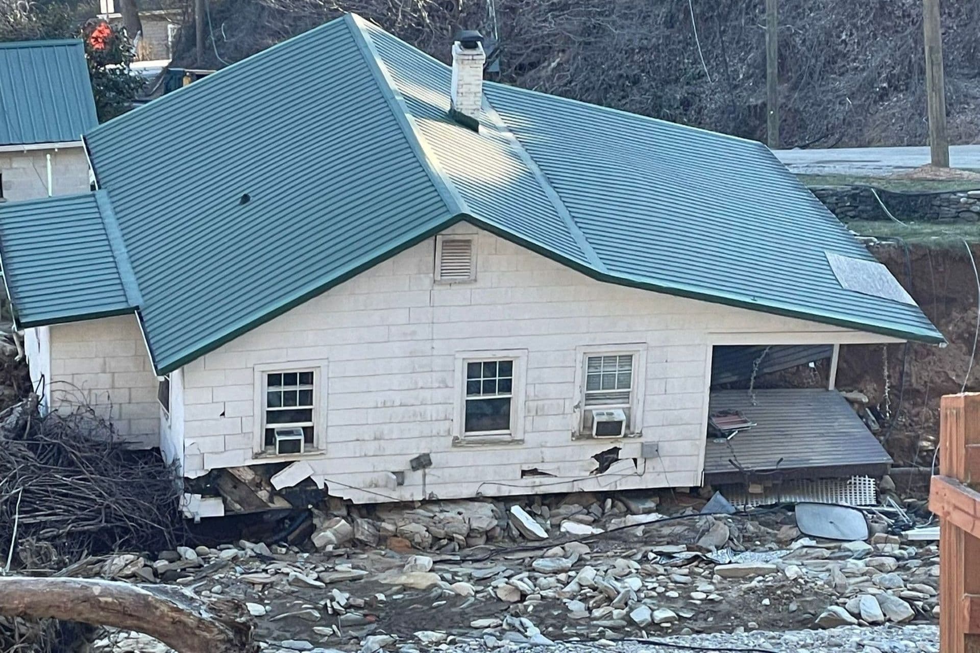A white post frame building damaged in a storm.