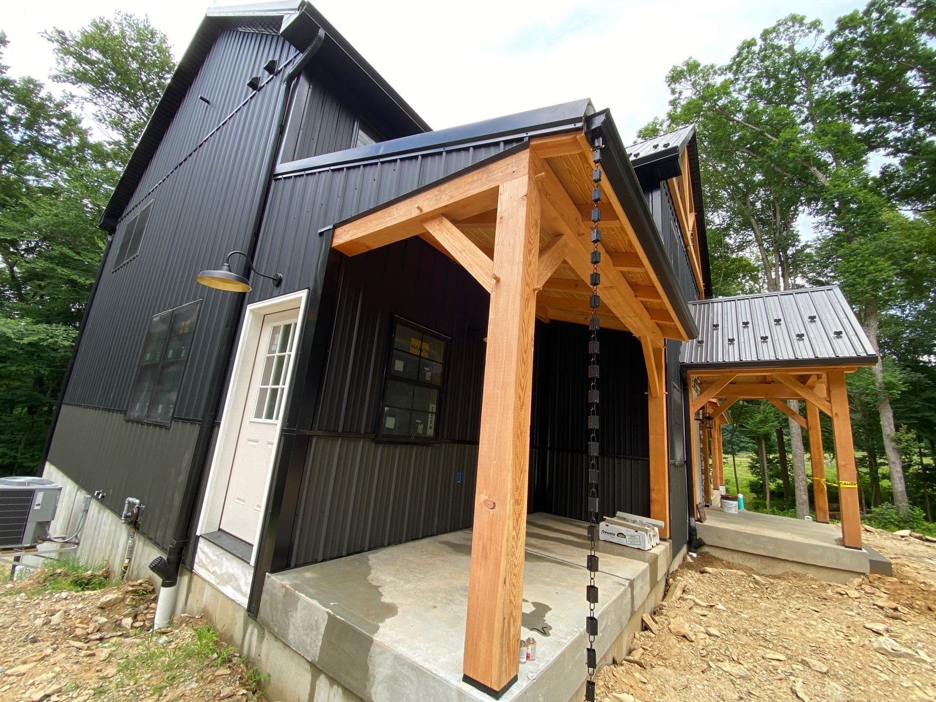 A black post frame building with black rain chains.