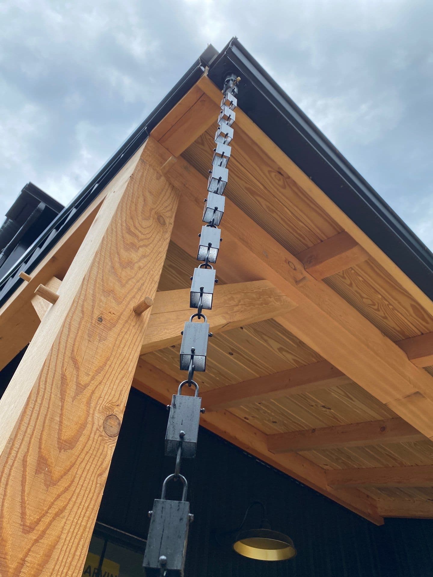 A black post frame building with black rain chains.