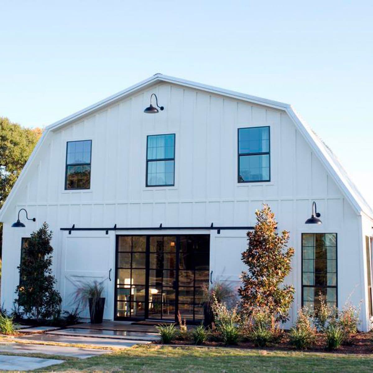 A white barndominium with glass doors and rolling barn doors.