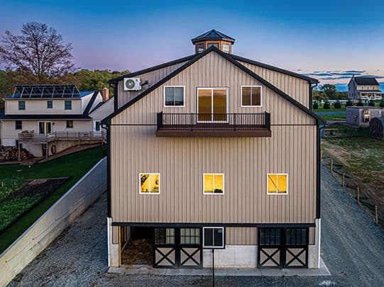 A rear view of a tan custom barndominium.