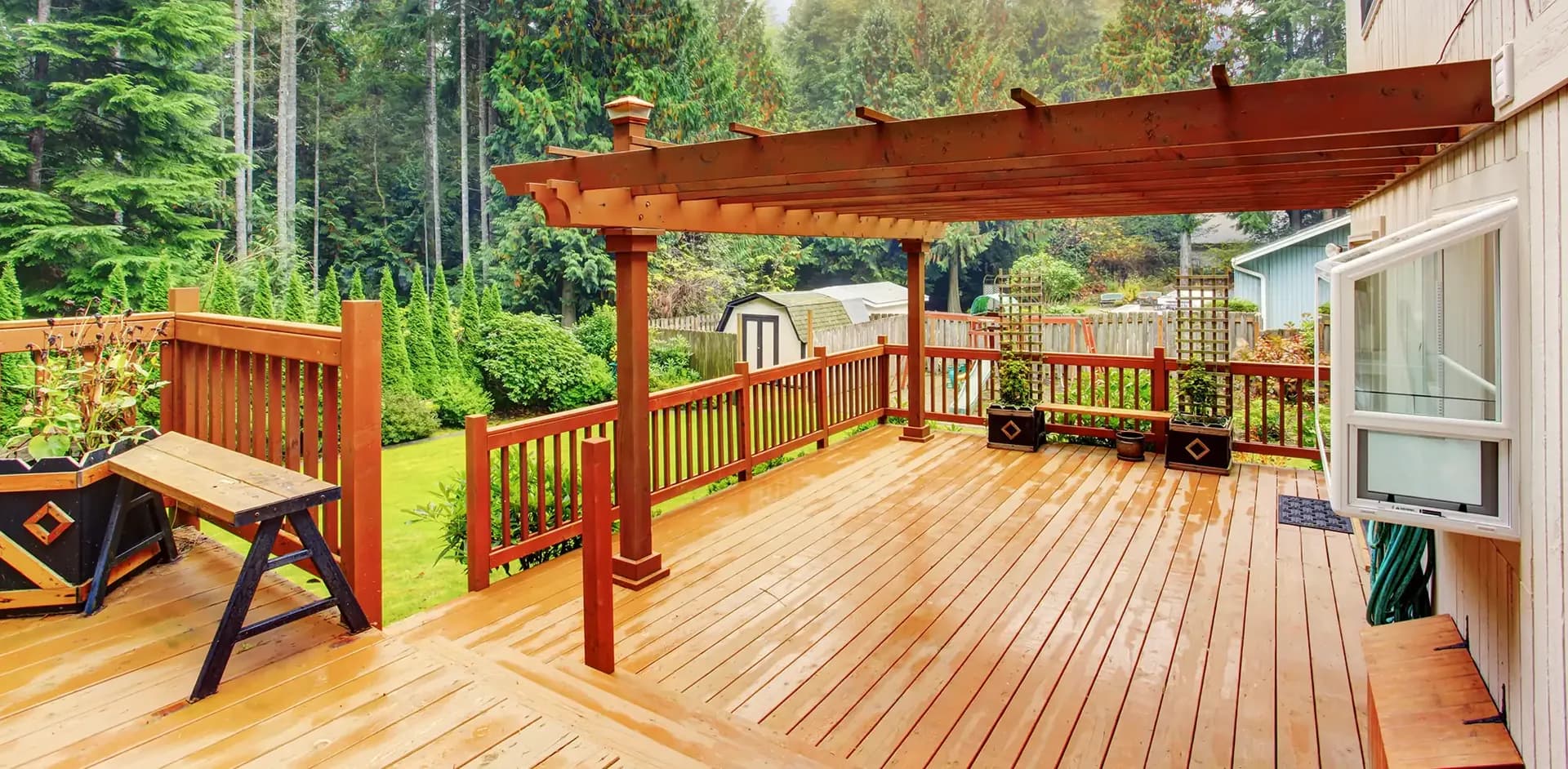 A medium brown deck with a pergola overlooking a yard.