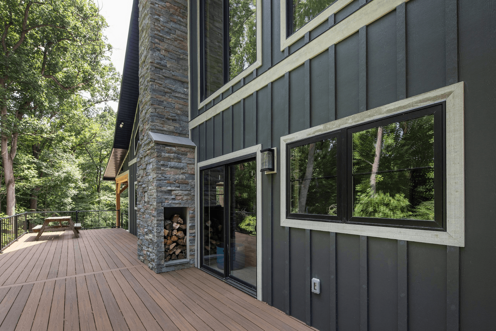 A deck on a house with sliding glass patio doors and a stone chimney with built-in firewood storage.