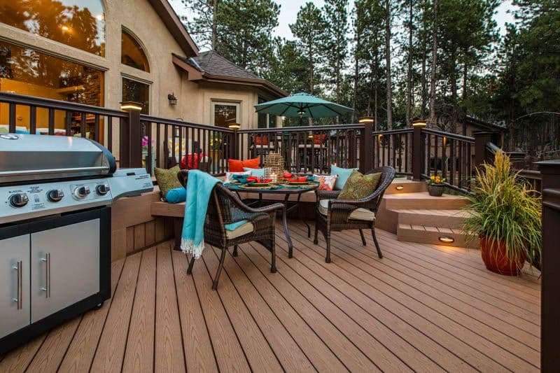 A brown deck with patio seating and a grilling area.