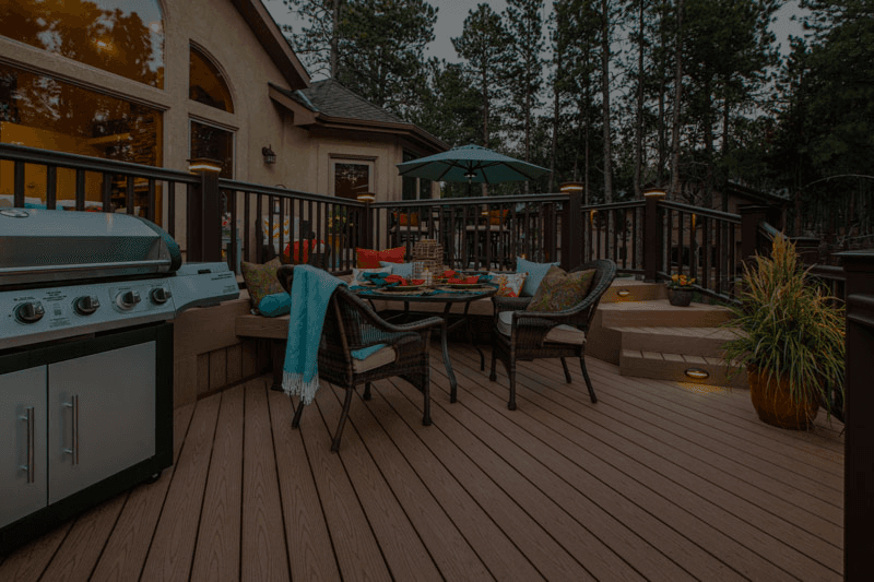 A brown deck with patio seating and a grilling area.