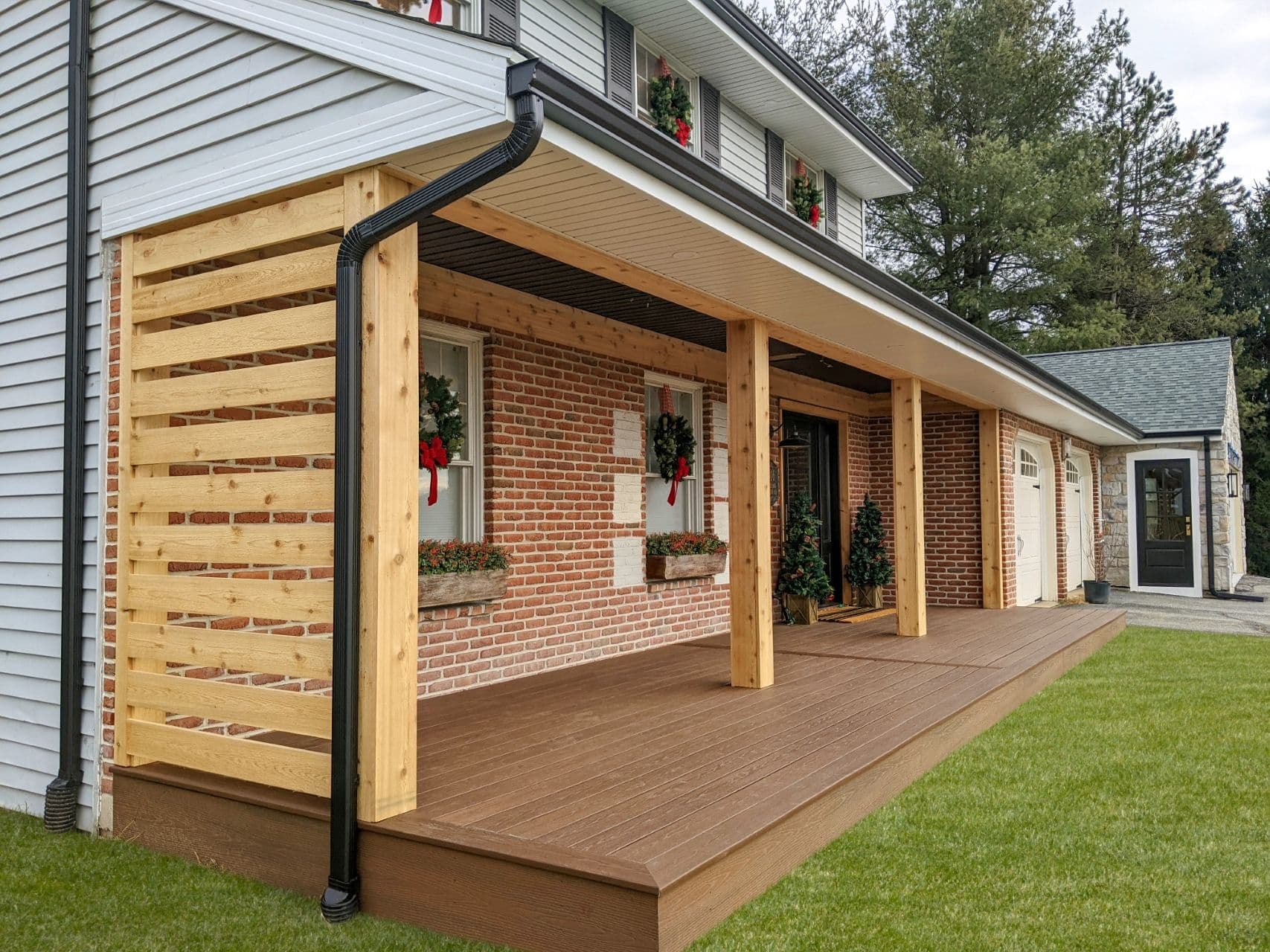 A new front porch deck on a white and red brick house.