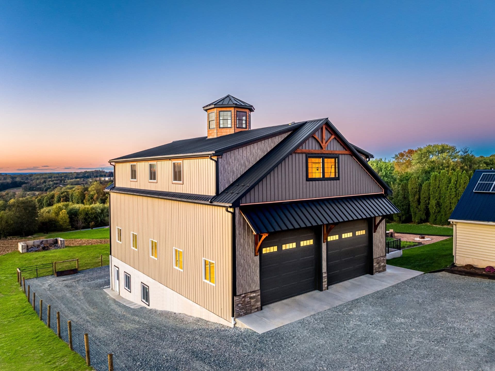 A custom built barn is lit up at sunset.
