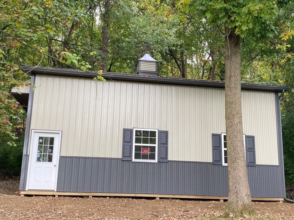 A post frame building with wainscoating and shutters.