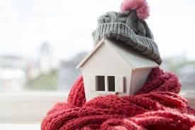 A birdhouse wrapped in a scarf and a winter hat.