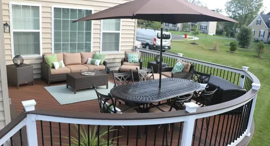 A curved deck with seating area and umbrella.