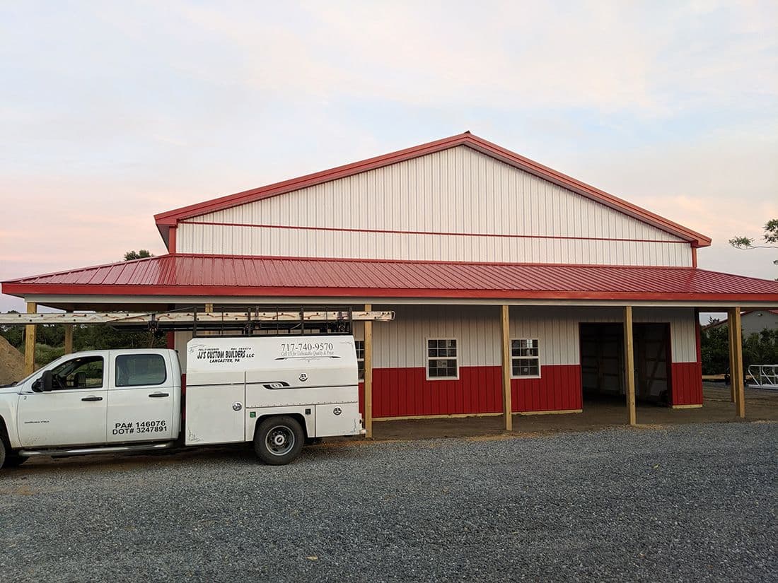 A red and white pole barn building with red metal roof.