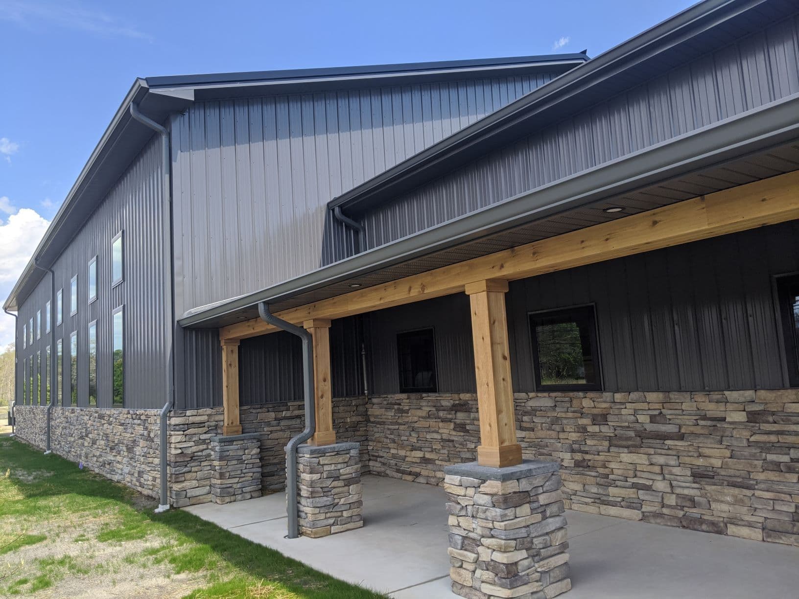 A gray metal pole barn building with stone foundation.