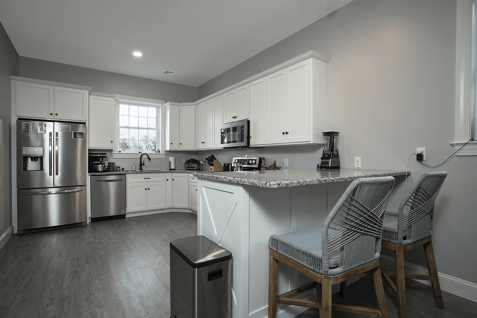 A gray kitchen with white cabinets and stainless steel appliances.