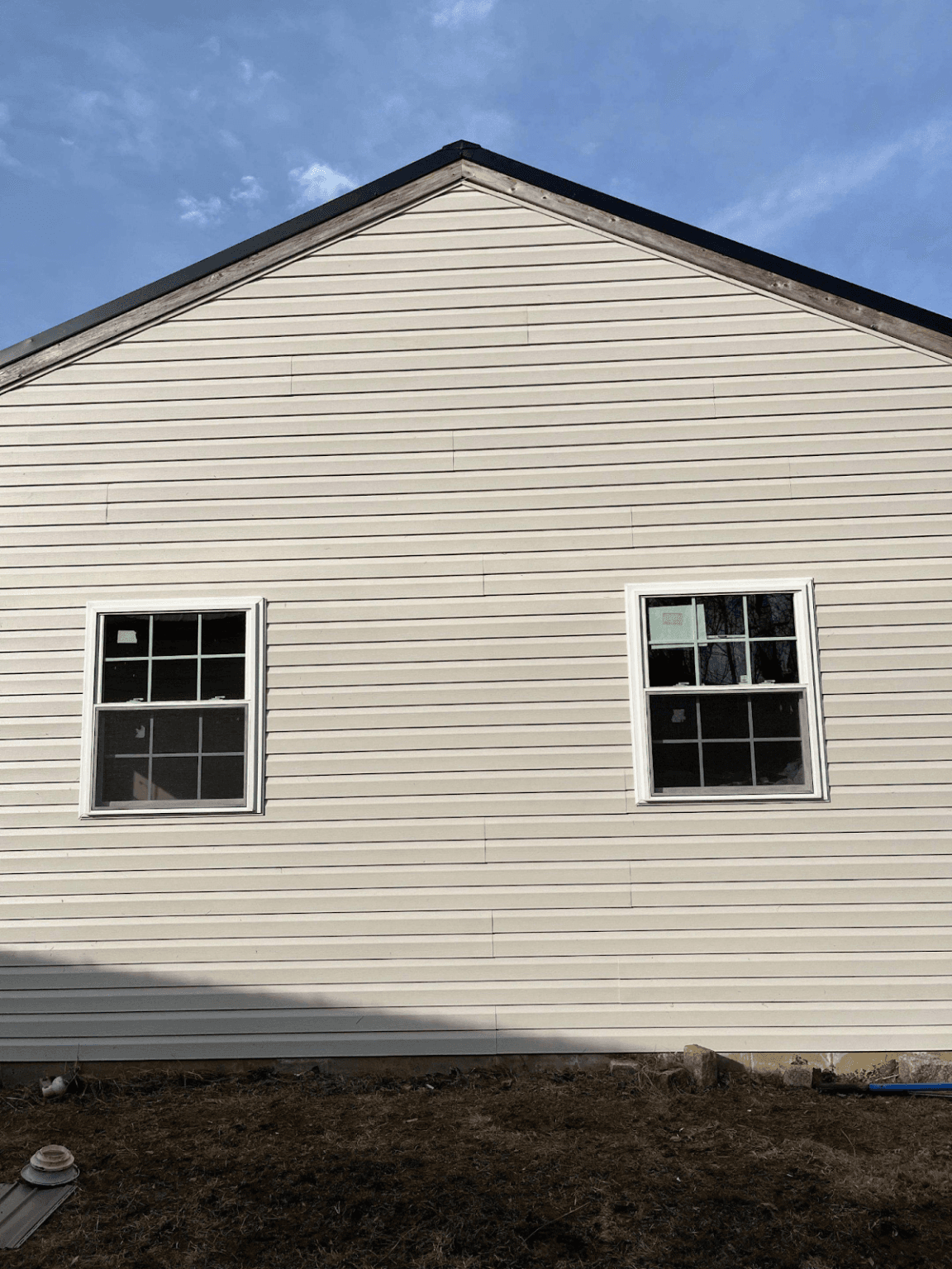 The side of a beige house with a newly-installed black metal roof.