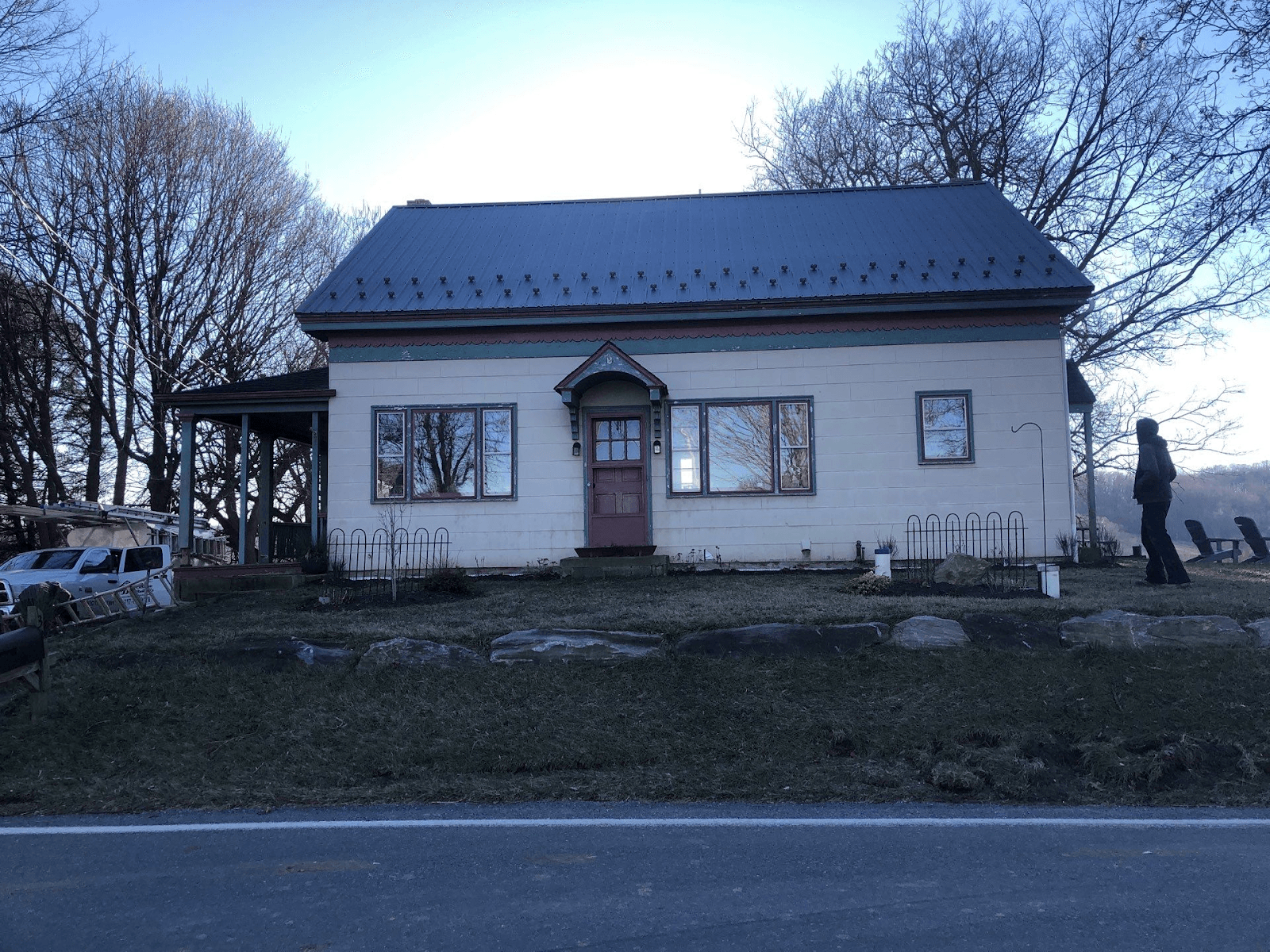 A light-colored house with red and green trim and a newly-installed metal roof.