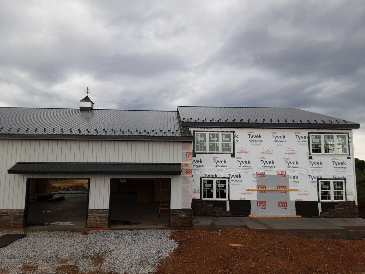A black and white post frame building in the middle of construction.