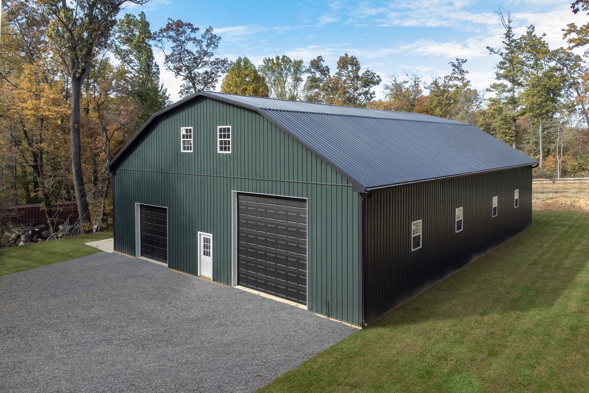 A large, dark green and black post frame building.