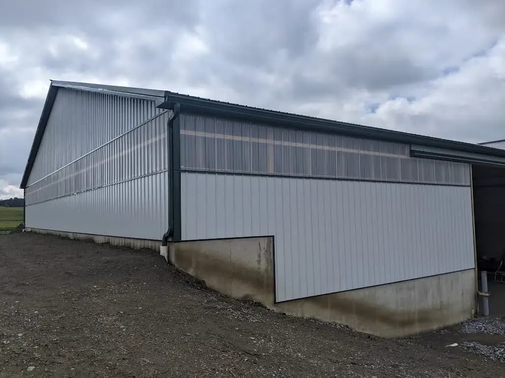 A gray and white agricultural post frame pole barn.