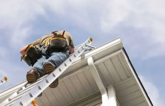 A roofer climbs a ladder.