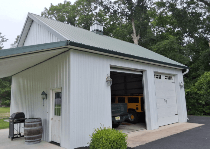 A white, two-car garage with a light green metal roof.
