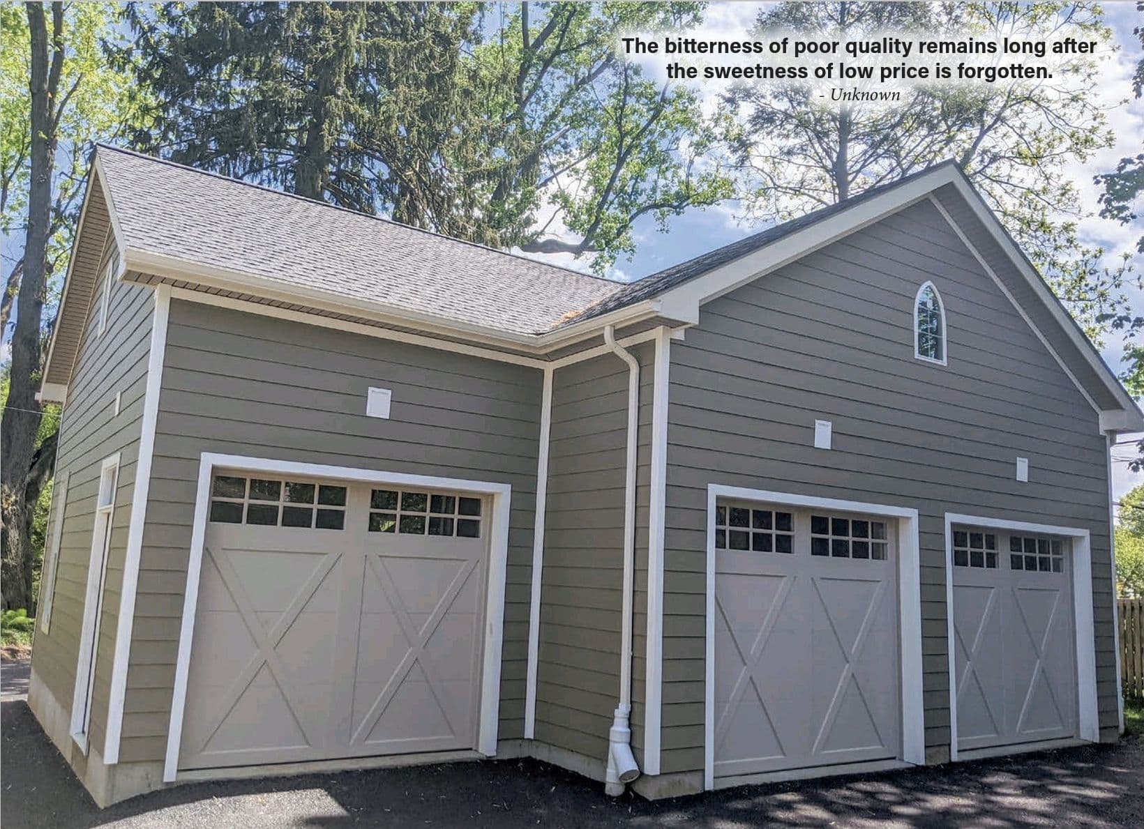 A gray and white detached garage with three bays.